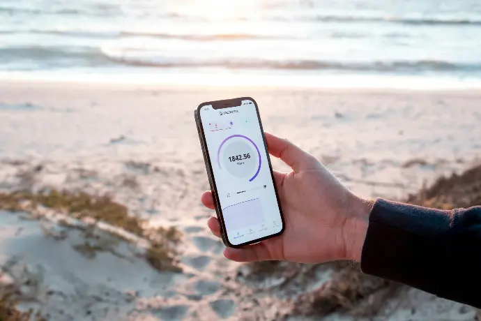 a person holding a cell phone with a beach in the background
